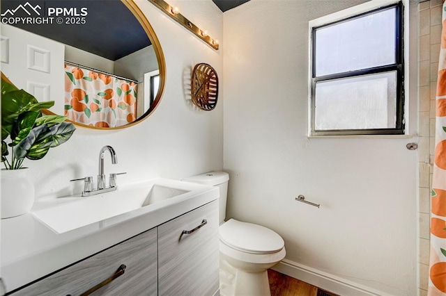 bathroom with vanity, wood finished floors, baseboards, curtained shower, and toilet