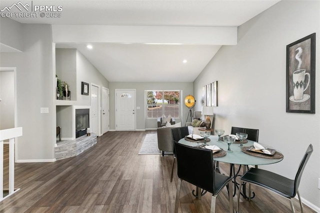 dining area featuring a glass covered fireplace, lofted ceiling with beams, baseboards, and wood finished floors