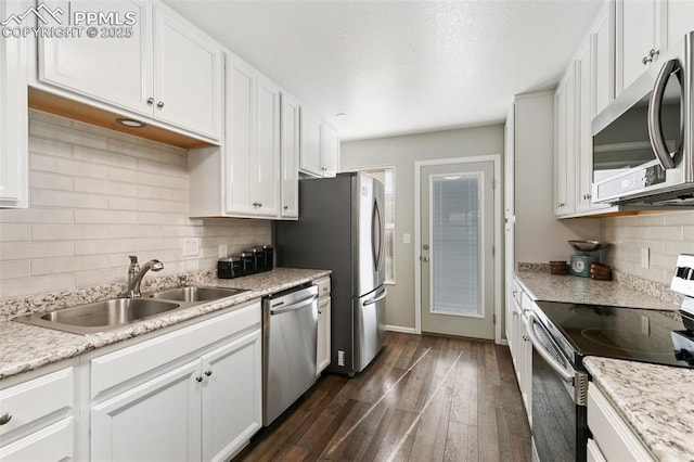 kitchen featuring appliances with stainless steel finishes, white cabinets, dark wood-type flooring, and a sink