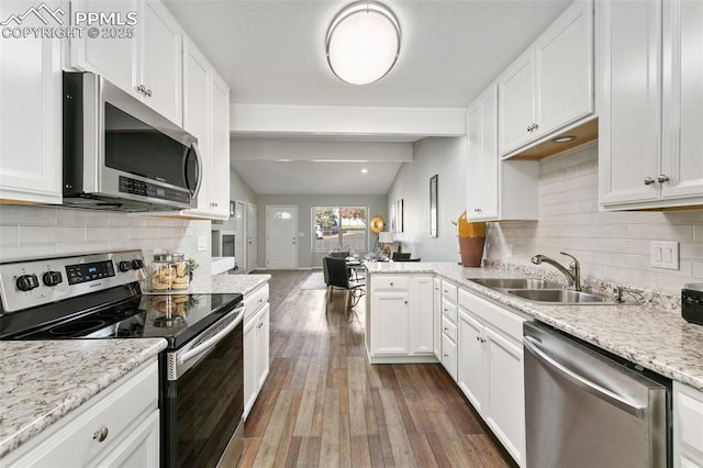 kitchen featuring lofted ceiling with beams, wood finished floors, a sink, white cabinetry, and appliances with stainless steel finishes