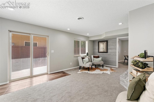 living area with a textured ceiling, carpet flooring, visible vents, and recessed lighting