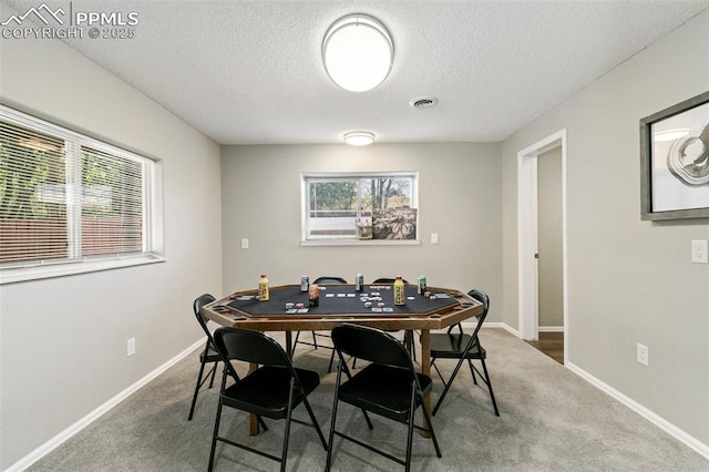 carpeted dining area featuring visible vents, a textured ceiling, and baseboards