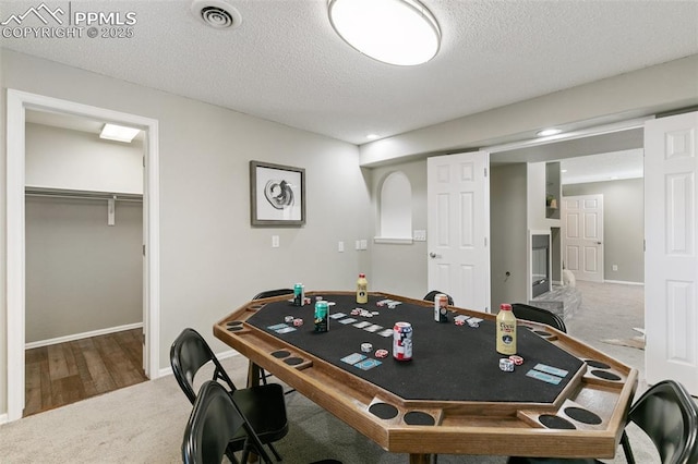 game room with carpet, visible vents, a textured ceiling, and baseboards