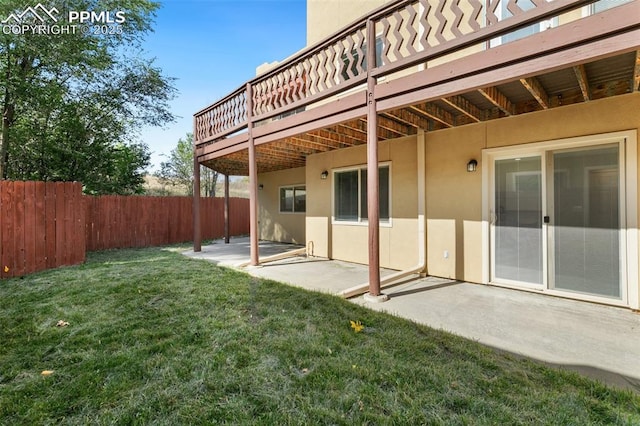 back of house featuring a patio, fence, a yard, a wooden deck, and stucco siding