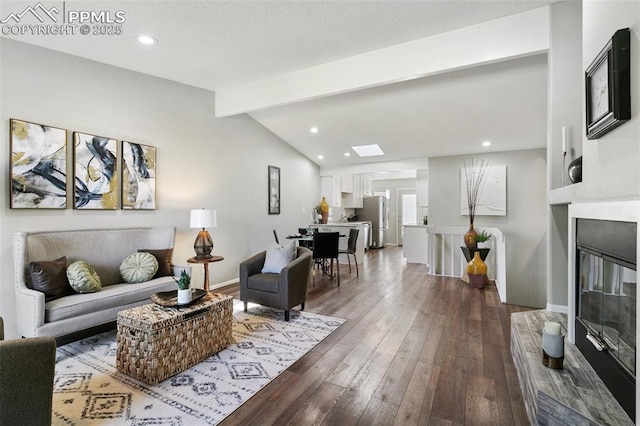 living room featuring lofted ceiling with skylight, recessed lighting, baseboards, and dark wood-style floors