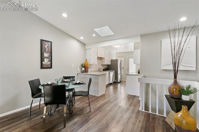 dining space featuring a skylight, baseboards, dark wood-type flooring, and recessed lighting