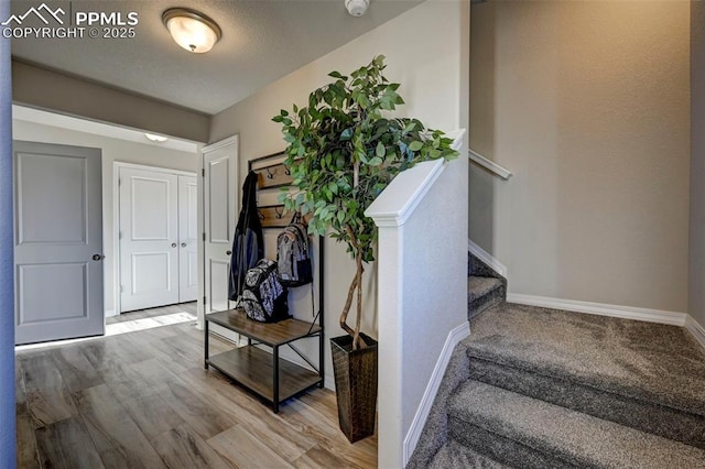 stairs featuring a textured ceiling, baseboards, and wood finished floors