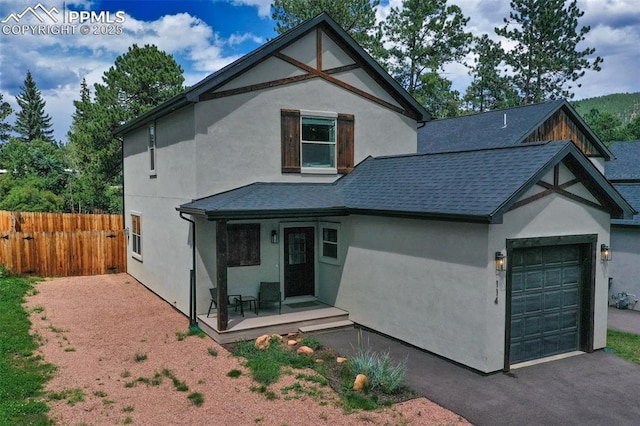 view of front facade with driveway, roof with shingles, an attached garage, fence, and stucco siding