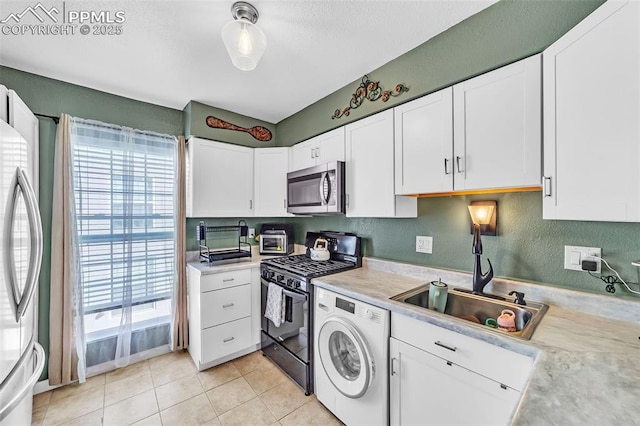 kitchen featuring appliances with stainless steel finishes, washer / clothes dryer, a sink, and light countertops