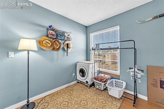 laundry room featuring laundry area, a textured ceiling, baseboards, and wood finished floors