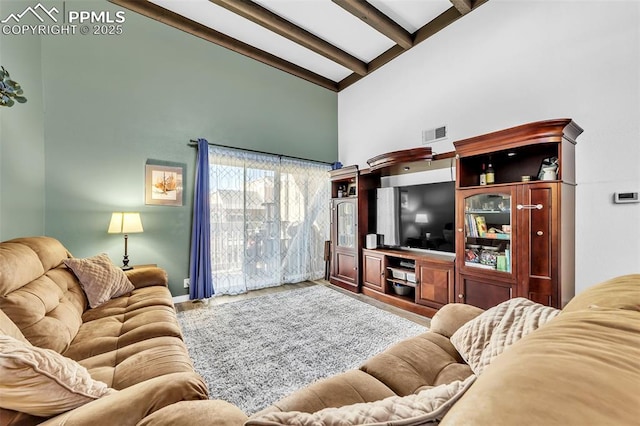 living area featuring beam ceiling, visible vents, and a high ceiling