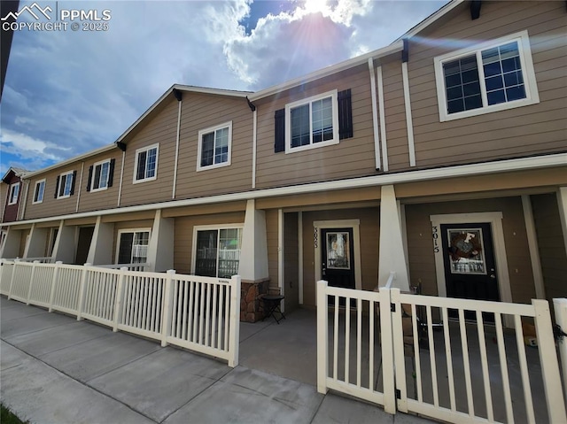 townhome / multi-family property featuring a porch and a fenced front yard