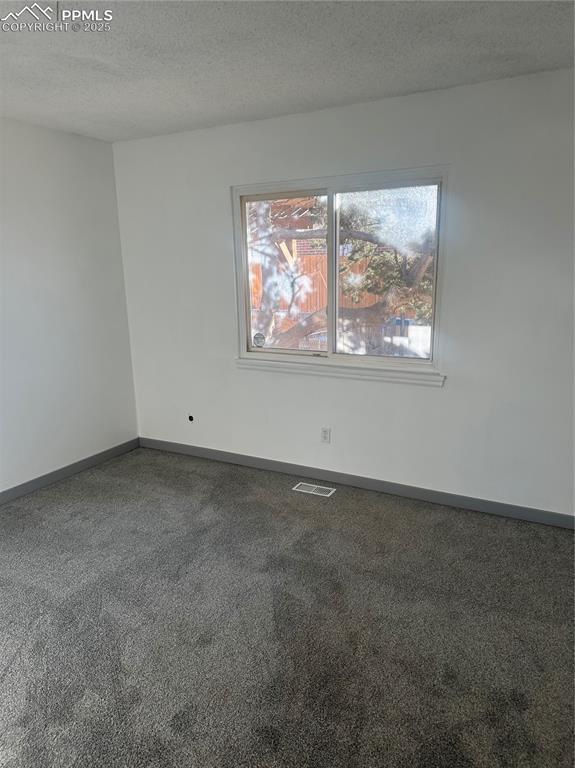 spare room with visible vents, a textured ceiling, and baseboards