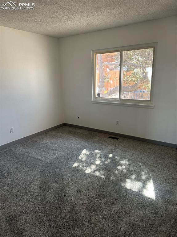 spare room featuring visible vents, baseboards, and a textured ceiling