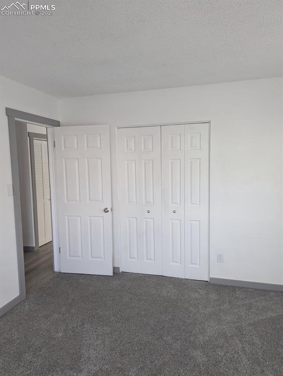 4211 Hunts Mill Ter, Colorado Springs, CO 80910 - unfurnished bedroom with carpet floors, baseboards, a closet, and a textured ceiling
