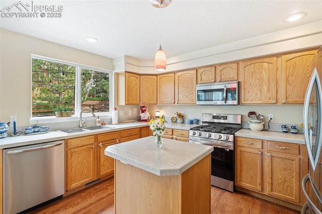 kitchen with stainless steel appliances, light countertops, a sink, and light wood-style flooring