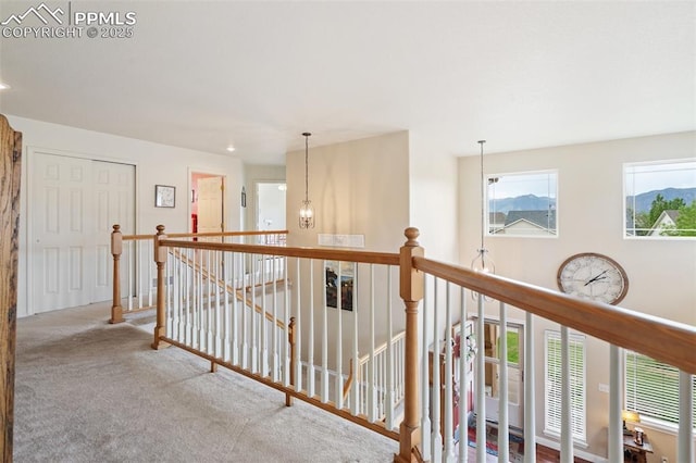 hall featuring carpet, an upstairs landing, and an inviting chandelier