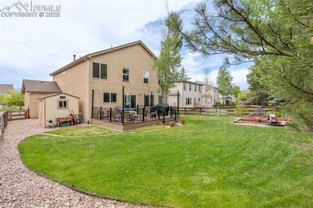 rear view of property featuring a fenced backyard, a yard, a deck, and stucco siding