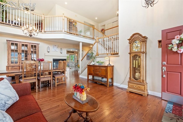 living room featuring stairs, a notable chandelier, wood finished floors, and baseboards