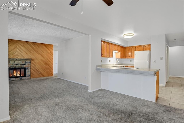 kitchen with light carpet, wood walls, a fireplace, open floor plan, and freestanding refrigerator