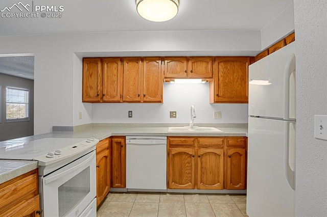 kitchen with white appliances, brown cabinets, and a sink