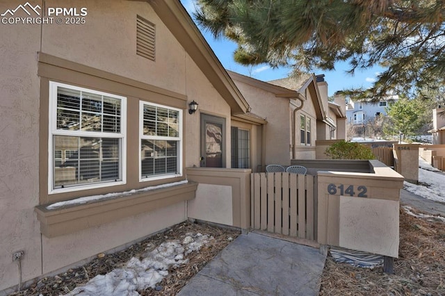 exterior space with a gate, fence, and stucco siding