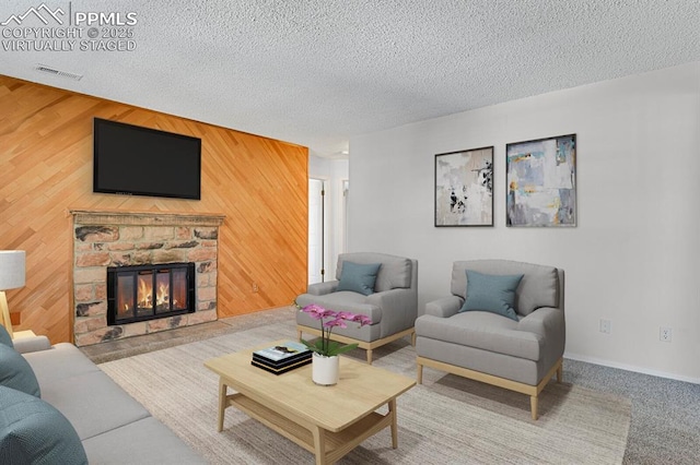 carpeted living room with a textured ceiling, a stone fireplace, wood walls, and visible vents