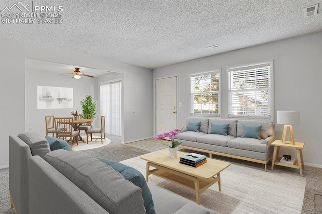 living room featuring visible vents, a textured ceiling, light colored carpet, and a healthy amount of sunlight