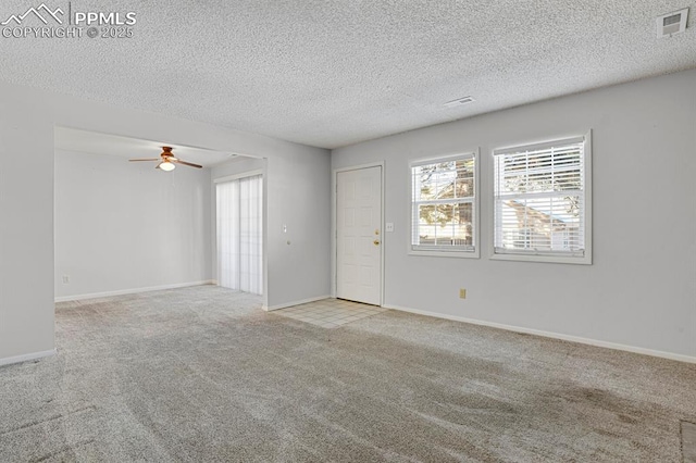 carpeted spare room featuring baseboards, visible vents, ceiling fan, and a textured ceiling