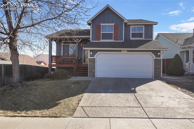 split level home with a garage, fence, driveway, stone siding, and board and batten siding