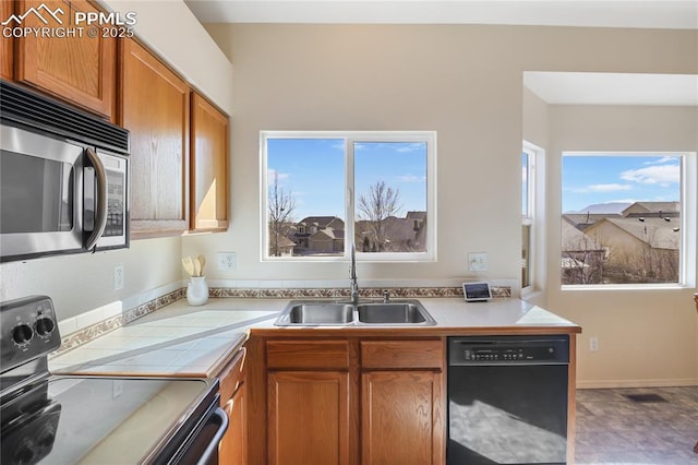 kitchen featuring visible vents, tile countertops, brown cabinets, black appliances, and a sink