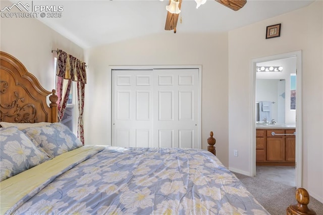 bedroom featuring a closet, light colored carpet, a ceiling fan, vaulted ceiling, and a sink