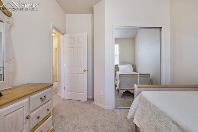 bedroom with baseboards, a closet, and light colored carpet