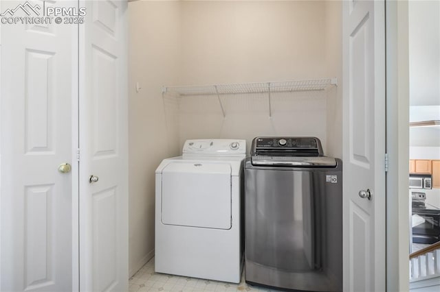 clothes washing area featuring laundry area, washer and clothes dryer, and light floors