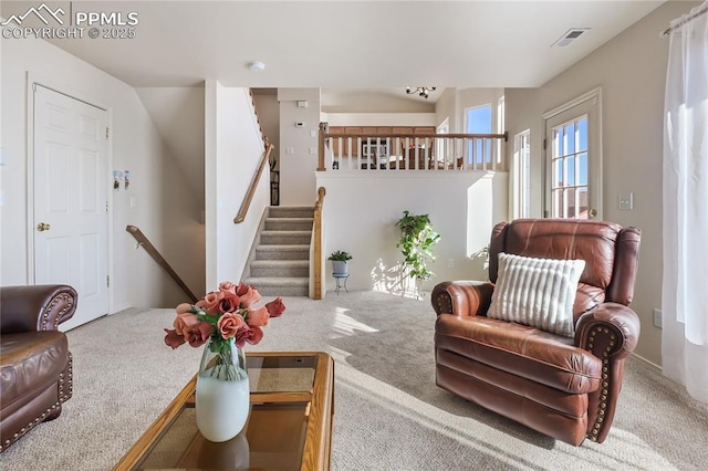 living room featuring stairs, visible vents, and carpet flooring