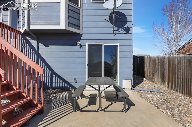 view of patio with stairs, outdoor dining space, and fence