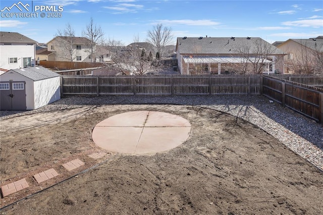 view of yard featuring a residential view, a fenced backyard, an outdoor structure, and a shed