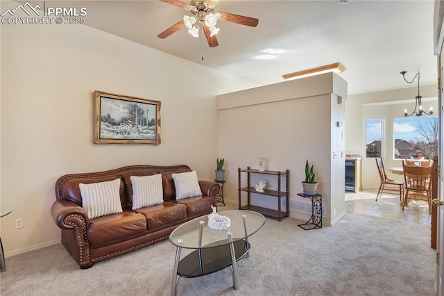 living area featuring carpet flooring, baseboards, and ceiling fan with notable chandelier