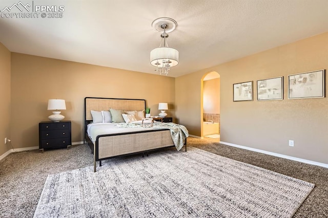 carpeted bedroom with a chandelier, arched walkways, connected bathroom, and baseboards