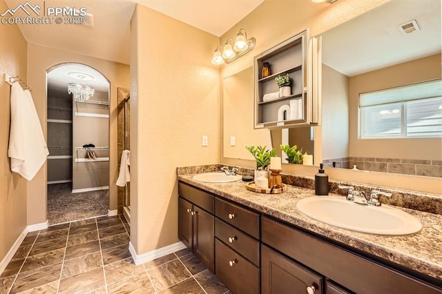 bathroom with double vanity, a sink, visible vents, and baseboards