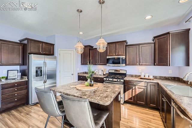 kitchen featuring stainless steel appliances, light wood-type flooring, a sink, and dark brown cabinetry