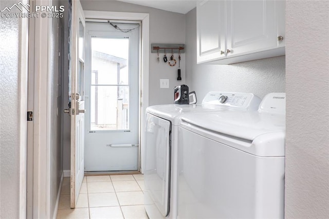 washroom featuring light tile patterned flooring, cabinet space, a textured wall, and separate washer and dryer