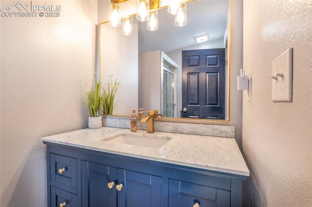 bathroom with lofted ceiling, a textured wall, and vanity