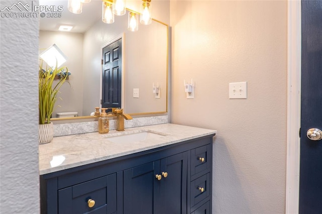 bathroom featuring toilet, a chandelier, and vanity