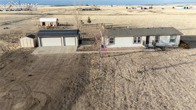 view of front of home featuring driveway, a garage, solar panels, fence, and an outdoor structure