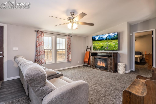 living room with baseboards, a glass covered fireplace, ceiling fan, vaulted ceiling, and carpet floors