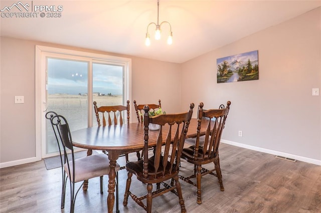 dining area with an inviting chandelier, baseboards, visible vents, and wood finished floors