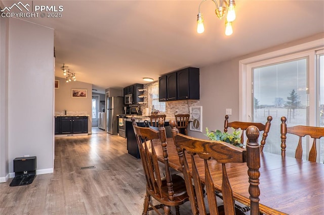 dining area featuring visible vents, an inviting chandelier, light wood-style flooring, and baseboards