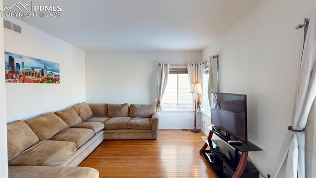 living area featuring light wood-style floors, visible vents, and baseboards