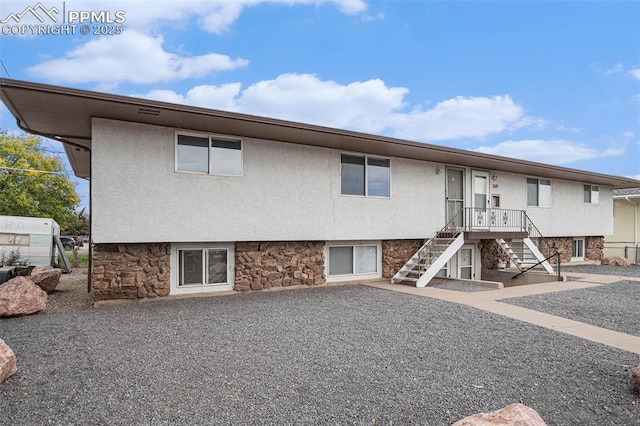 view of front of home with stone siding, stairway, and stucco siding